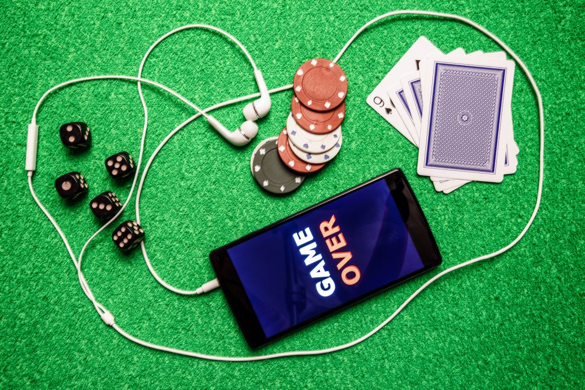 Casinos Accessories and gambling concept on the green background. Smartphone with an inscription game over as symbol to play gambling.