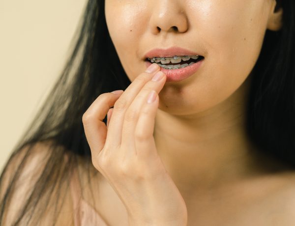 Close up view of woman with braces touching her lips