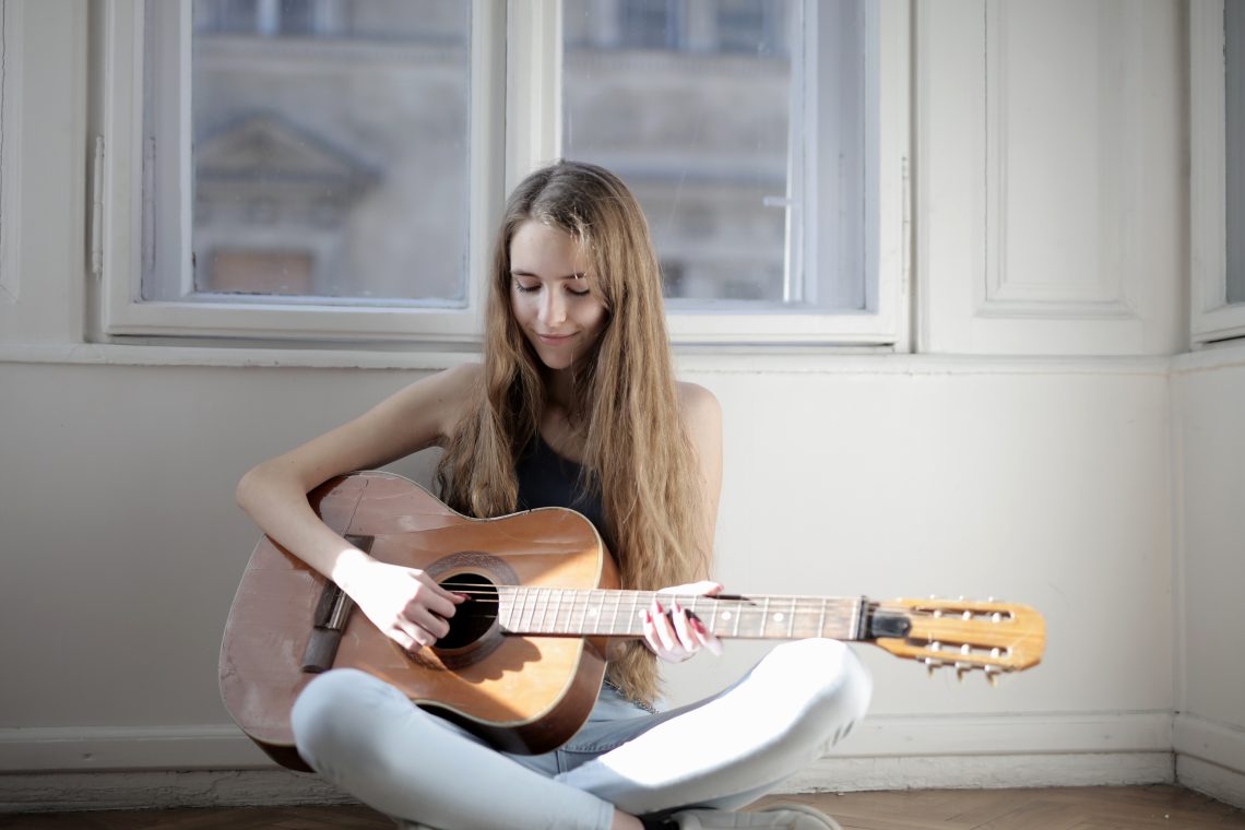 Woman playing brown acoustic guitar