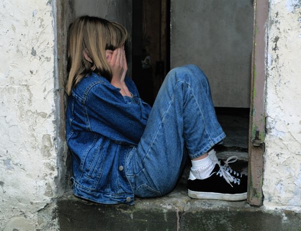 Lonely girl sitting on a doorway