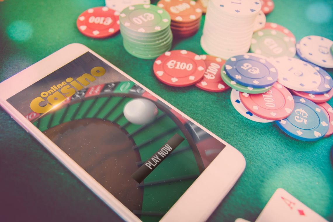 smartphone with poker website on screen, chips over green poker table
