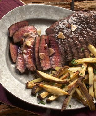 Photo of steak and french fries on gray plate