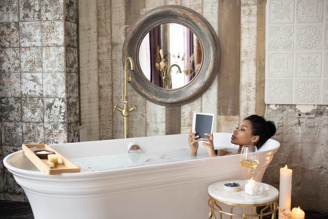 Black woman reading book while taking bath