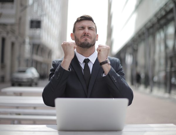 Man in black suit sitting on chair beside buildings