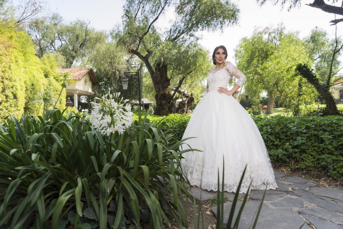 Woman in white wedding dress standing near green plants