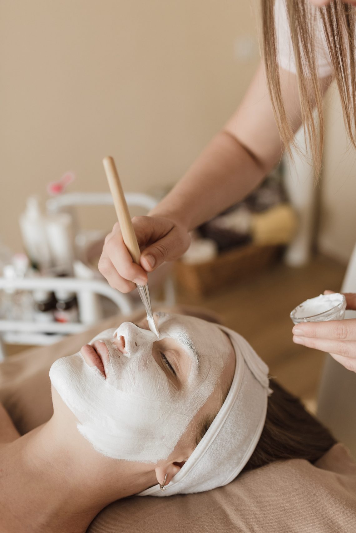 A person applying facial mask on a womans face
