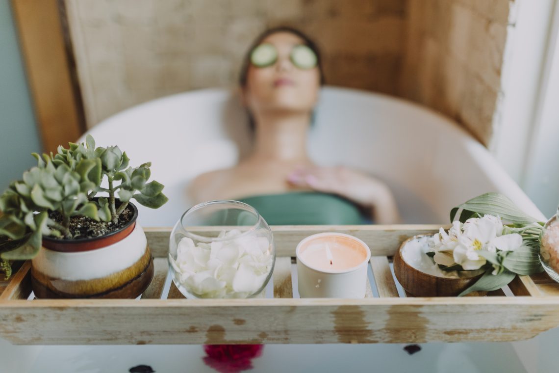 Woman in green tube top sitting on white ceramic bathtub