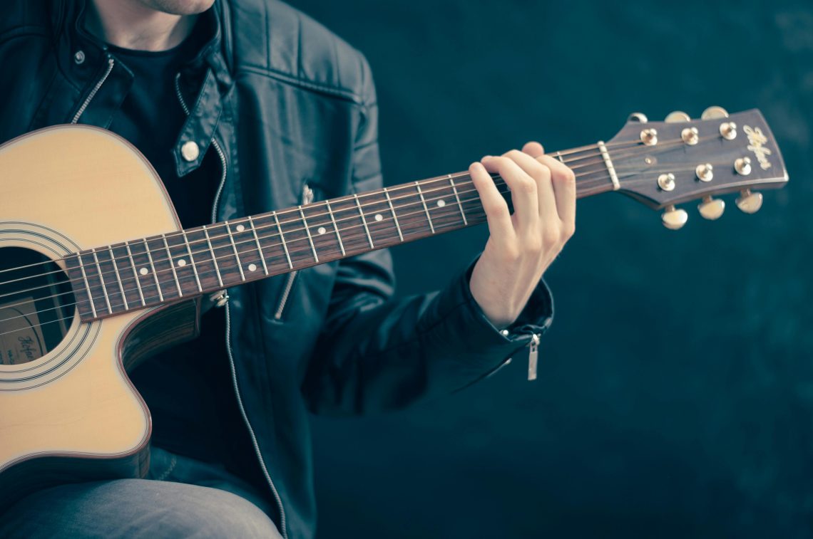 Person holding brown and black guitar