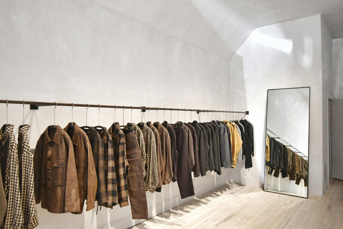 A room with a mirror and a closet bar packed with men’s clothes