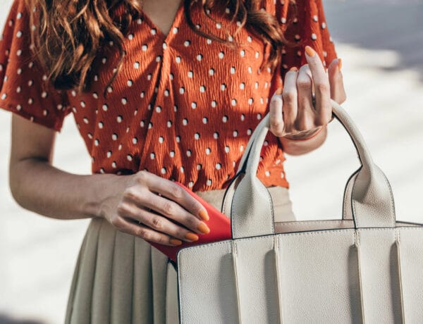 cropped shot of woman putting smartphone into female bag