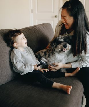 Happy mother and child sitting on sofa with their pet dog