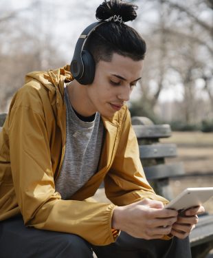 Young man with earphones and tablet on street