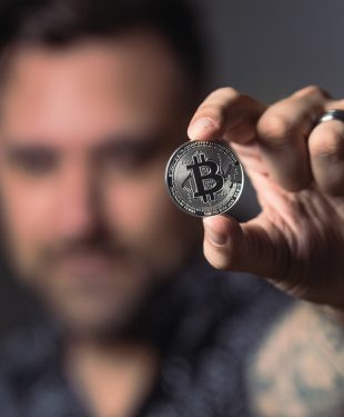 Person holding silver bitcoin coin