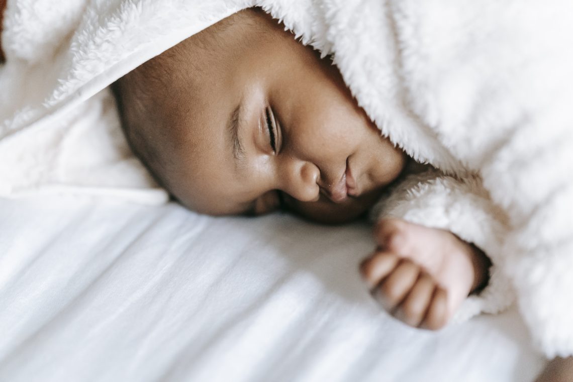 Sleeping newborn black baby lying on bed