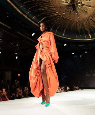 Woman in orange robe standing on white floor