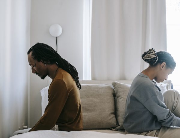 Concerned black couple sitting on bed in misunderstanding