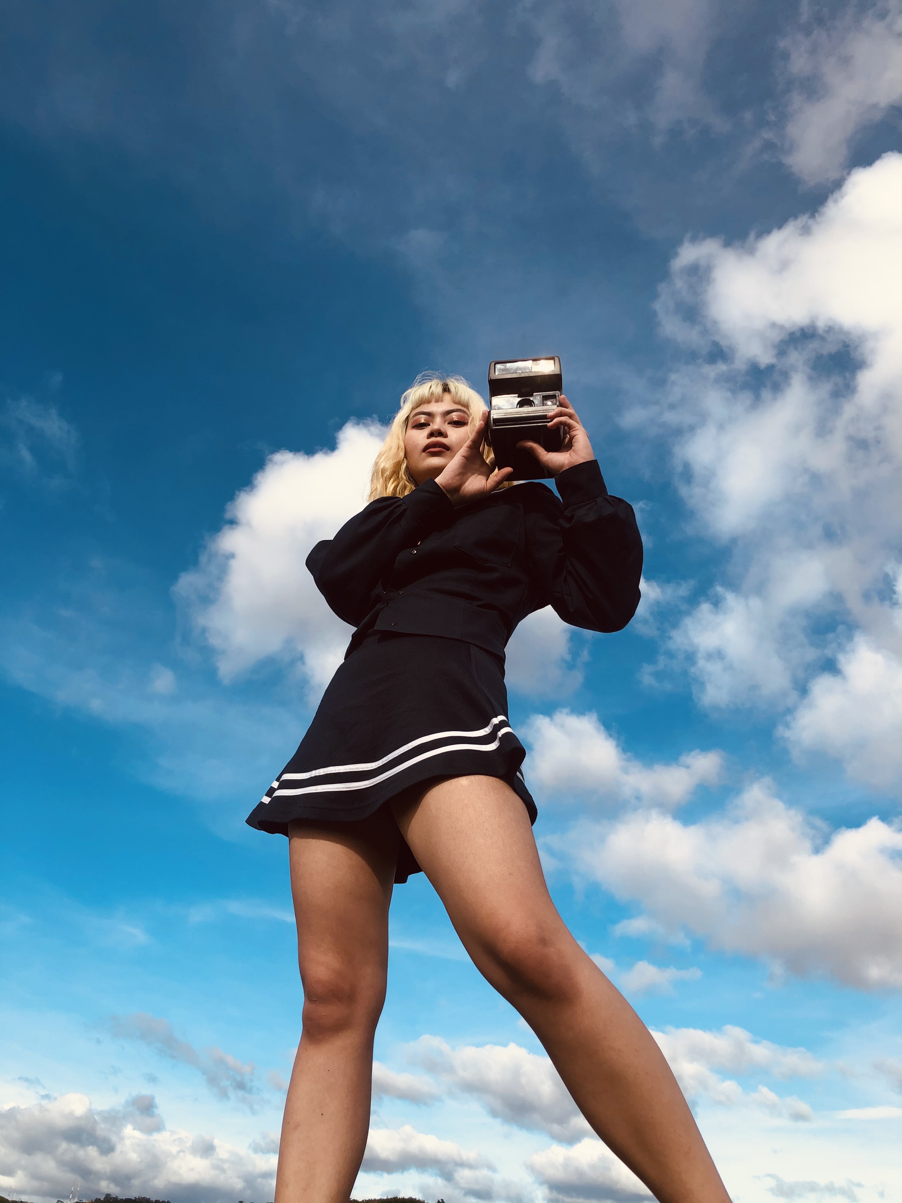 Ethnic female standing with photo camera in nature