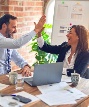 Two middle age business workers smiling happy and confident. Working together with smile on face hand giving high five at the office