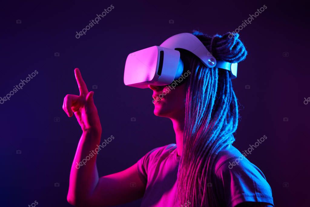 Woman is using virtual reality headset. Neon light studio portrait.
