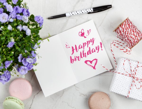 Happy birthday card beside flower thread box and macaroons