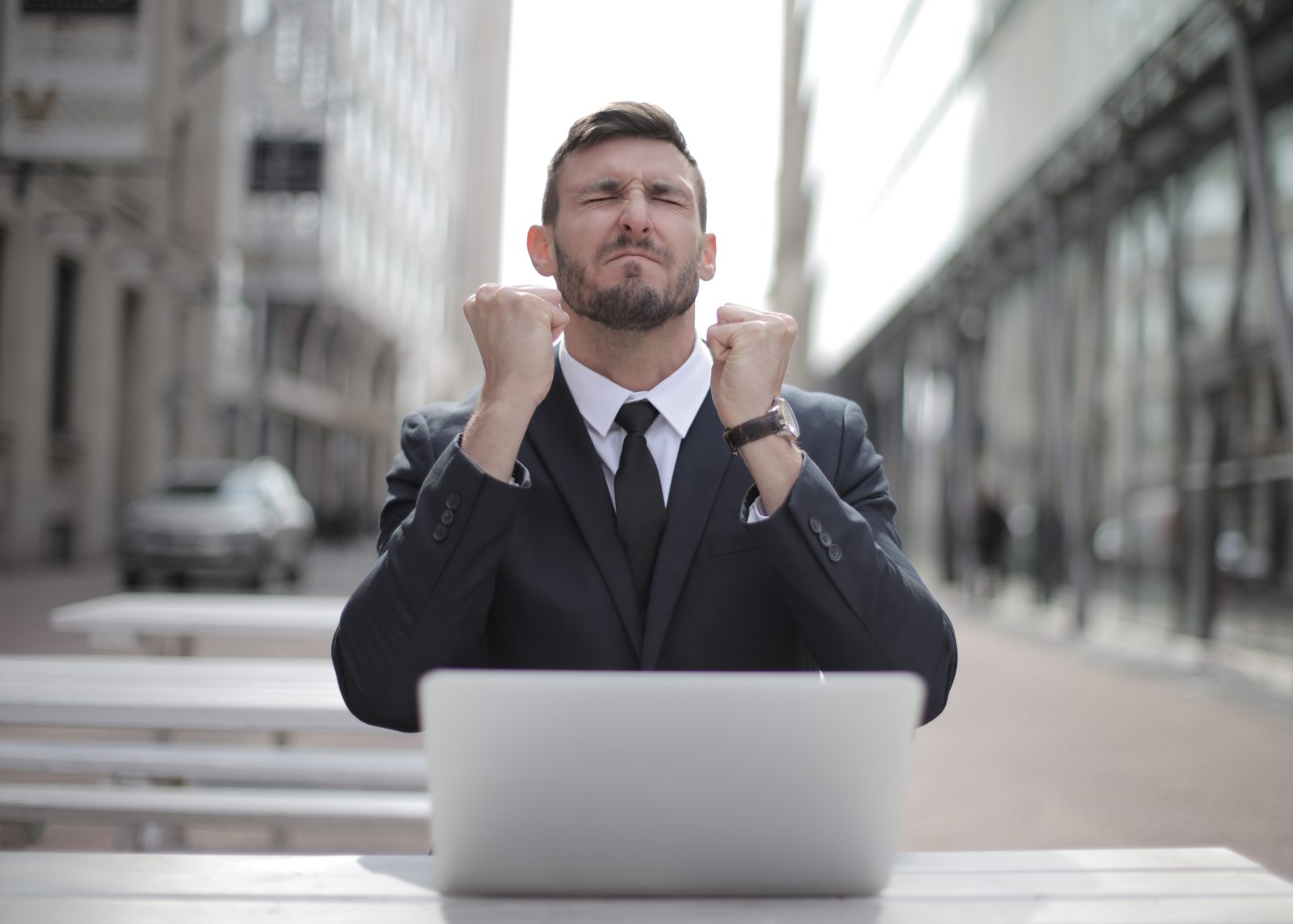 Man in black suit sitting on chair beside buildings