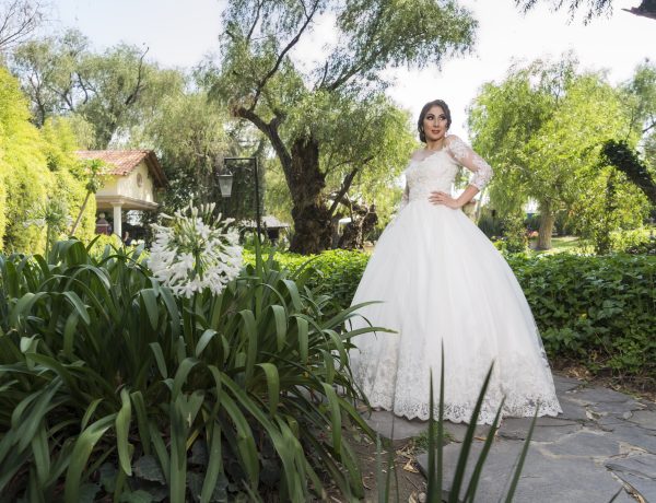 Woman in white wedding dress standing near green plants