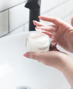 Woman using face cream in bathroom at sink