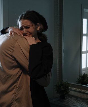 An emotional woman crying while hugging another person