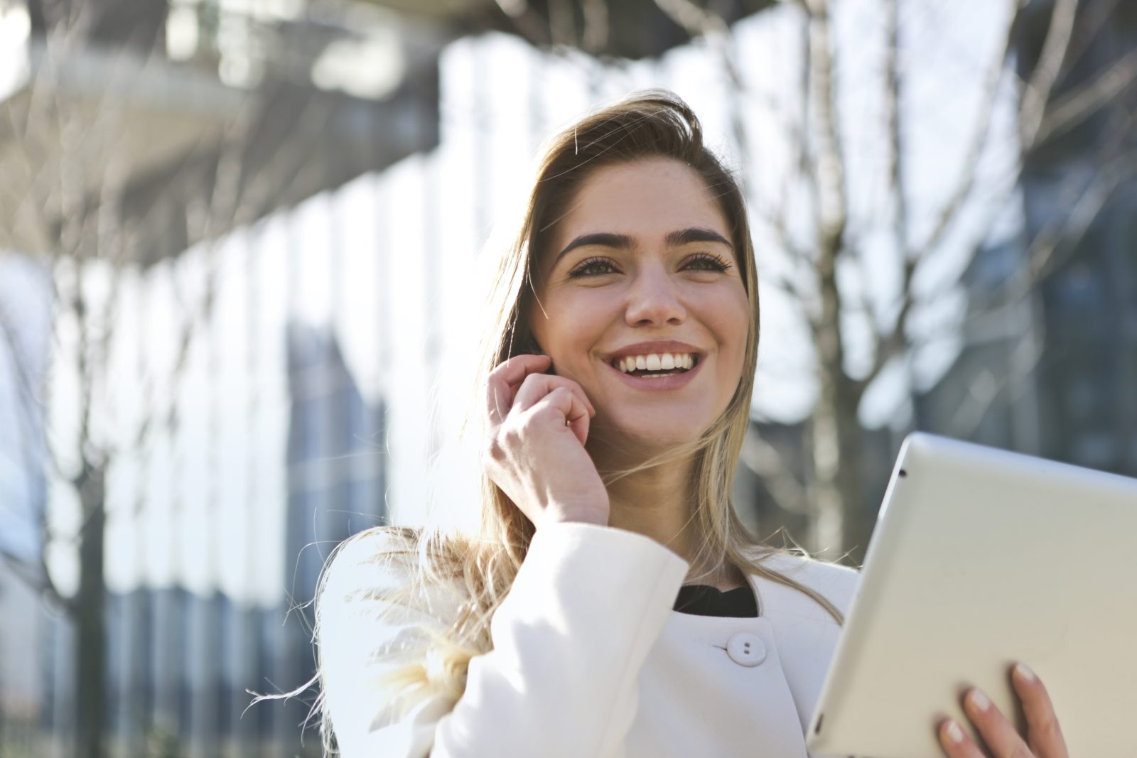 Woman in white blazer holding tablet computer