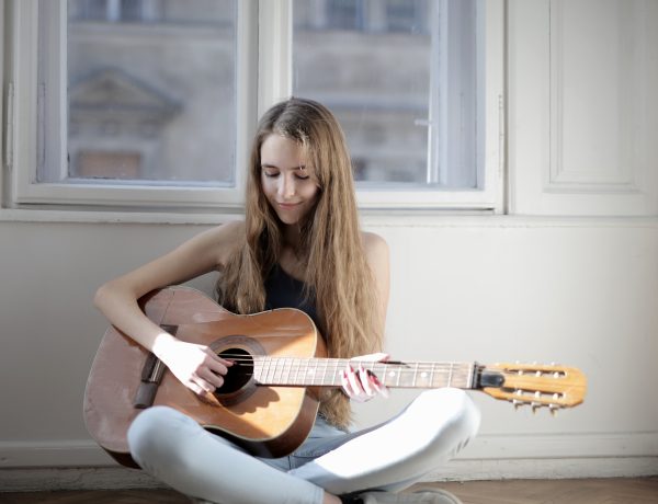 Woman playing brown acoustic guitar