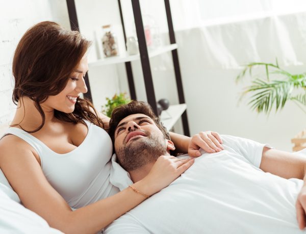 happy girlfriend looking at boyfriend lying on bed