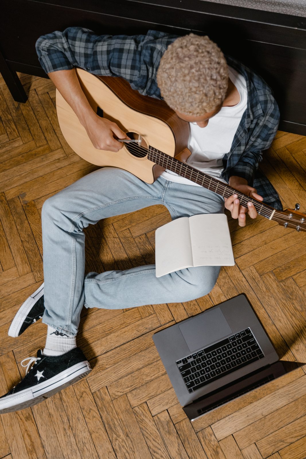 A man composing a song while holding his acoustic guitar