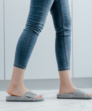 A person in blue denim jeans and grays slippers