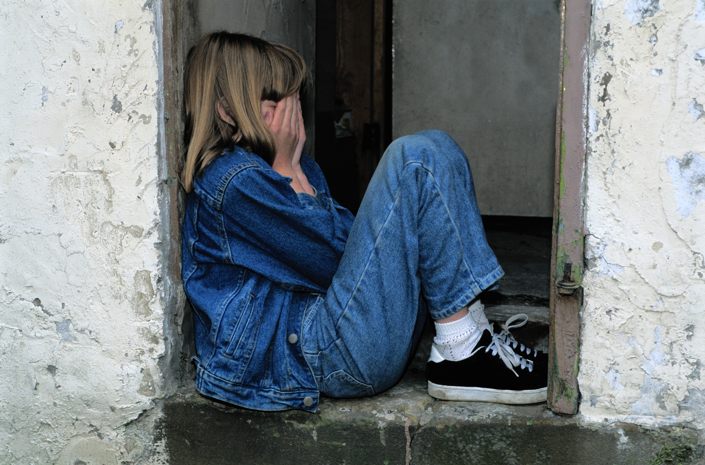 Lonely girl sitting on a doorway