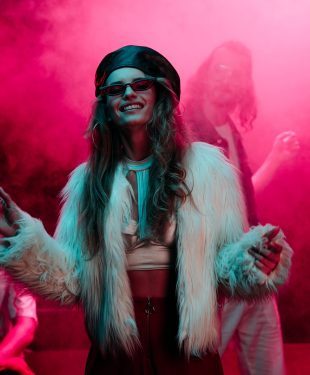 cheerful girl dancing in nightclub with pink smoke