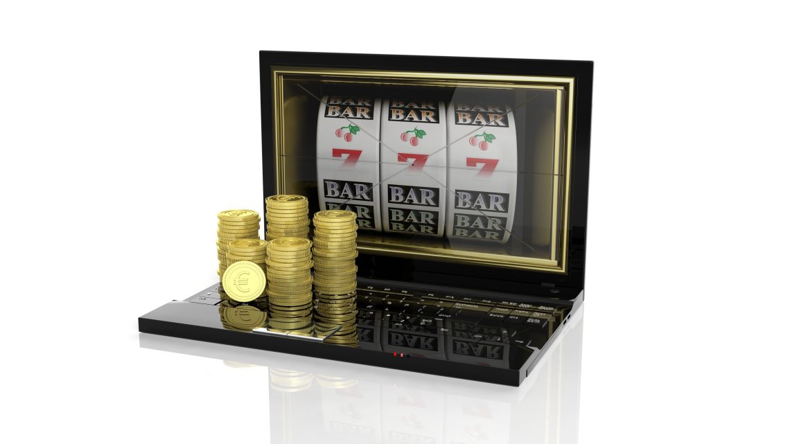 Stacks of golden Euro coins on laptop with 777 slots on screen, isolated on white background.