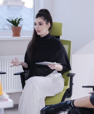 A woman sitting on a chair with her legs crossed while having conversation