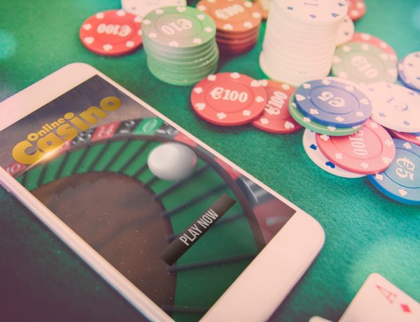 smartphone with poker website on screen, chips over green poker table