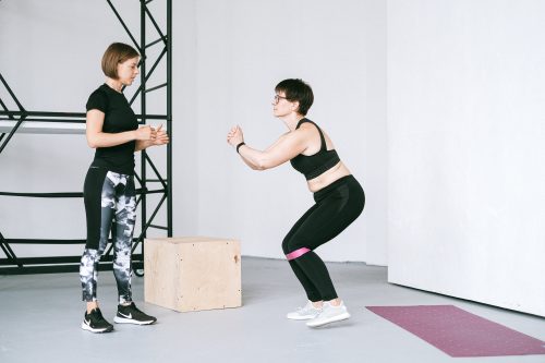 A woman supervising an elderly woman exercise