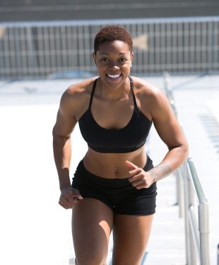 Woman wearing black sports bra and jogger shorts smiling