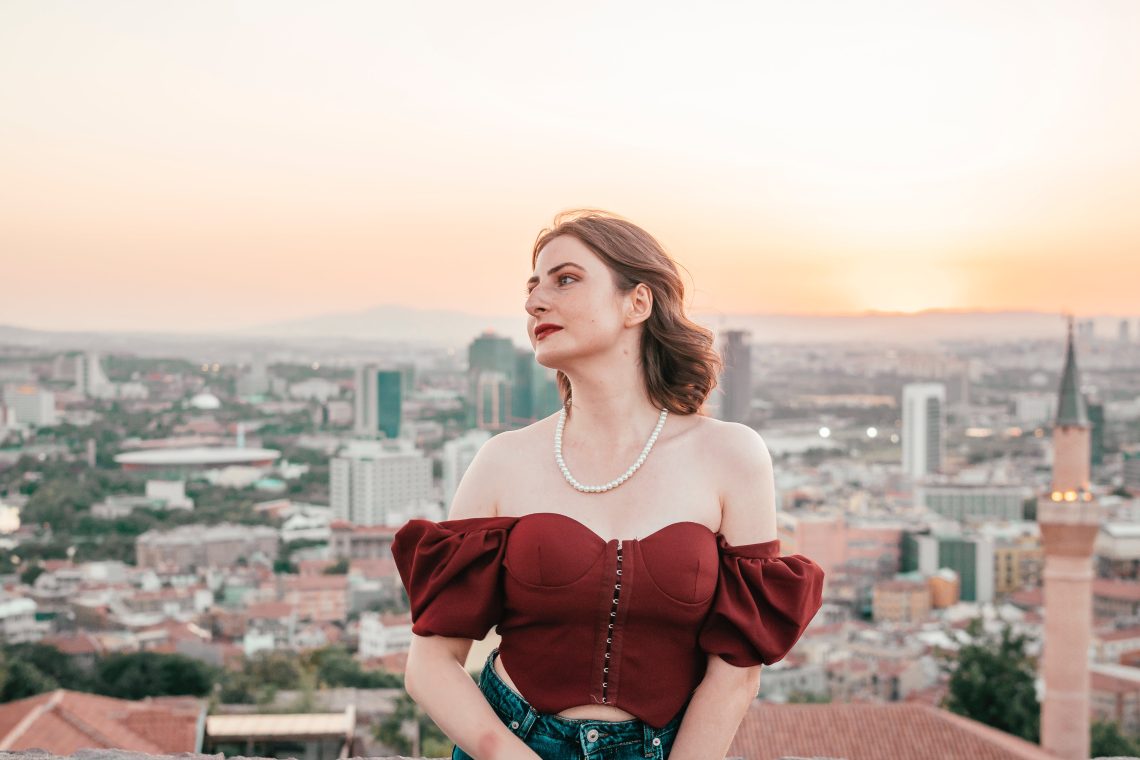Young elegant woman sitting on the background of a city at sunset